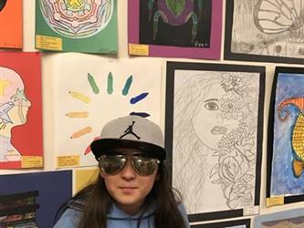 A student with sunglasses standing in front of art pieces