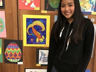 A girl standing in front of a collection of student art