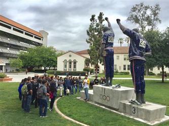 Students next to a monument of Tommie Smith and John Carlos
